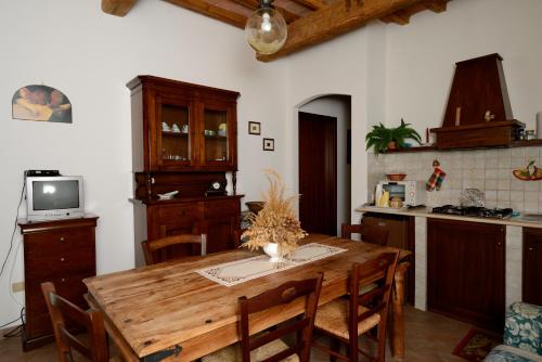 cocina con mesa de madera con sillas y TV en L'Antico Casale Di Sandro, en Acquasparta