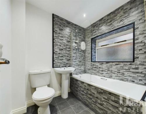 a bathroom with a toilet and a tub and a sink at Modern two bed apartment in Hull