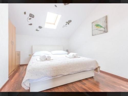 a white bedroom with a bed with two towels on it at Banić Apartments with pool in Biograd na Moru