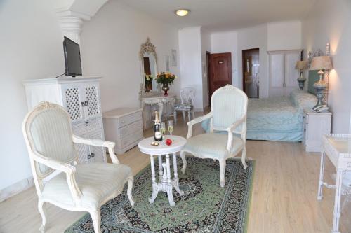 a bedroom with white chairs and a table and a bed at Misty Waves Boutique Hotel in Hermanus