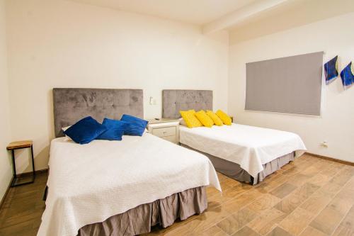 two beds in a room with blue and yellow pillows at Quinta San Carlos Ensenada in Ensenada