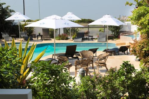 a pool with chairs and tables and umbrellas at Misty Waves Boutique Hotel in Hermanus