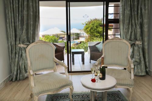 a room with two chairs and a table with wine glasses at Misty Waves Boutique Hotel in Hermanus