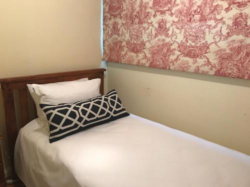 a bed with a pillow and a painting on the wall at Belltrees - Central, Cosy and Convenient in Armidale