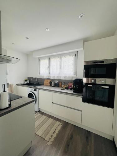 une cuisine avec des armoires blanches et un four à plaques de cuisson dans l'établissement Superbe appartement lumineux avec parking gratuit, à Wintzenheim