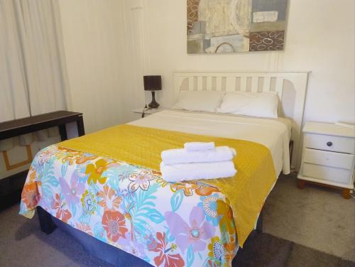 a bedroom with a bed with a yellow blanket at Classic Queenslander Suite in Townsville