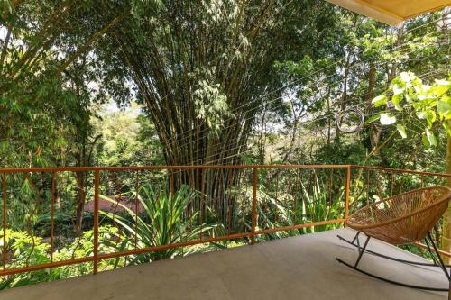 a balcony with a chair and trees in the background at Restful Casa Quetzal Luxurious Rainforest Retreat in Quepos