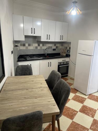een keuken met een tafel, stoelen en een koelkast bij Appart malabata in Tanger