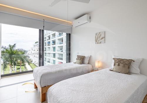 two beds in a room with a large window at Hermoso departamento, Vista al mar, 2 recámaras 516 in Nuevo Vallarta