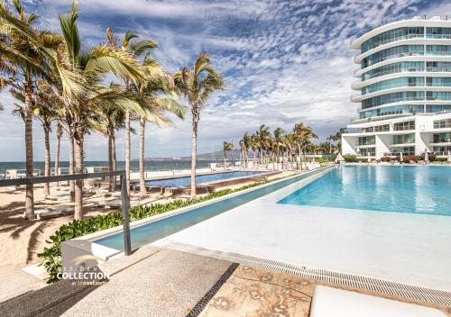a swimming pool with palm trees and a building at Hermoso departamento, Vista al mar, 2 recámaras 516 in Nuevo Vallarta