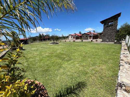 a large yard with a house in the background at Cabañas El Pedregal in Huasca de Ocampo