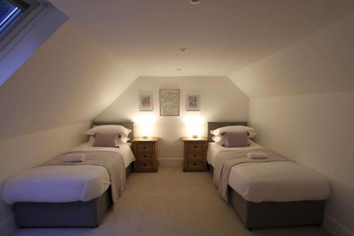a bedroom with two beds and two night stands at Peaceful Cotswolds Cottage - Stow-on-the-Wold, Owl Cottage in Wyck Rissington