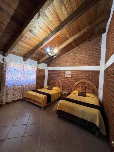 two beds in a room with a brick wall at Cabañas El Pedregal in Huasca de Ocampo