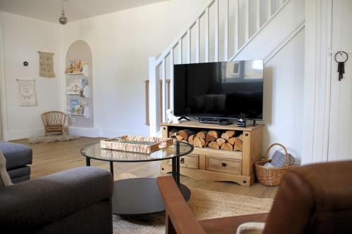 a living room with a tv and a coffee table at Peaceful Cotswolds Cottage - Stow-on-the-Wold, Owl Cottage in Wyck Rissington
