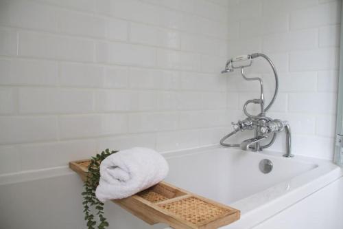 a bath tub with a towel on the side of it at Peaceful Cotswolds Cottage - Stow-on-the-Wold, Owl Cottage in Wyck Rissington