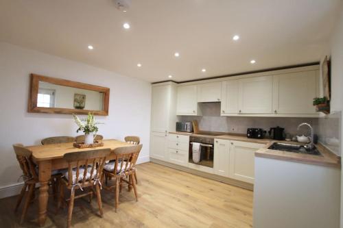 a kitchen with a wooden table and a wooden floor at Peaceful Cotswolds Cottage - Stow-on-the-Wold, Owl Cottage in Wyck Rissington