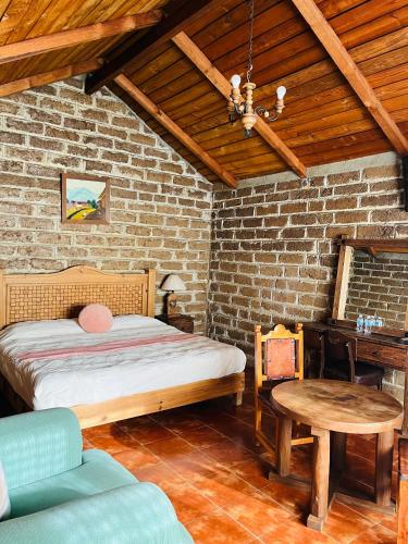 a bedroom with a bed and a brick wall at Cabañas Los Cactus in San Miguel Regla
