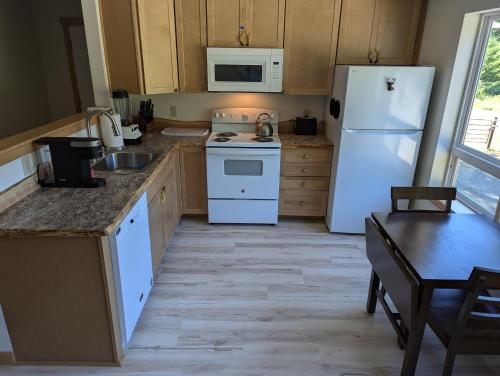 a kitchen with white appliances and a wooden floor at Bugling Elk Bungalow in Packwood