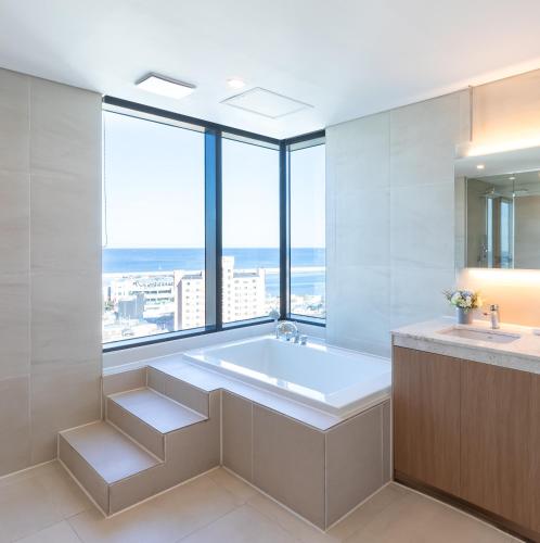 a bathroom with a tub and a large window at SL Hotel Gangneung in Gangneung