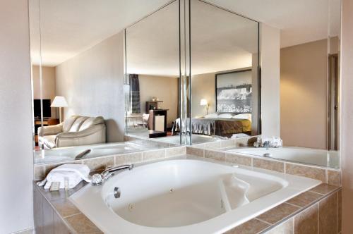 a bathroom with a large tub and a large mirror at Super 8 by Wyndham Niagara Falls in Niagara Falls