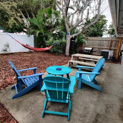 a patio with blue chairs and a table and a hammock at Paradise Beach Oasis in Indialantic