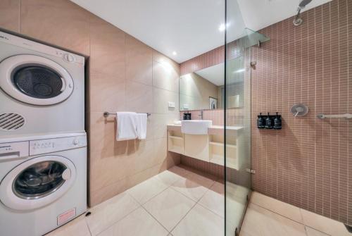 a bathroom with a washing machine in a shower at Sensation Sunsets Seaviews I Mantra' Central CBD Apartment in Darwin