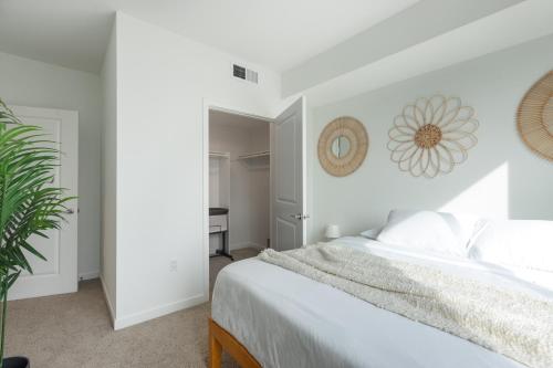 a white bedroom with a bed and a plant at Beautiful 1BR Apt in Hollywood w Pool and Parking in Los Angeles