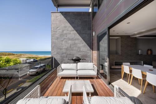 a living room with a white couch on a balcony at Luxury in Paradise - Sea views and Beach in Mount Maunganui