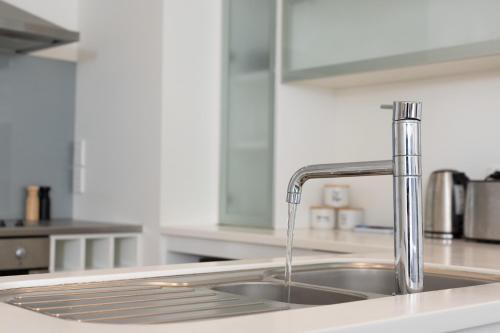 a kitchen sink with water coming out of it at Sunny and Spacious - moments from the Beach and Downtown in Mount Maunganui