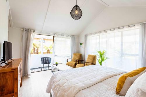 a bedroom with a bed and a tv and a window at Spacious, Breezy Studio Apartment, Moments from Downtown and Beach in Mount Maunganui