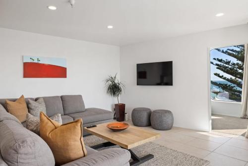 a living room with a couch and a table at Oceanside Bliss - Absolute Beachfront - Uninterrupted Ocean Views with Pool in Mount Maunganui