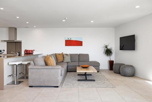 a living room with a couch and a table at Oceanside Bliss - Absolute Beachfront - Uninterrupted Ocean Views with Pool in Mount Maunganui