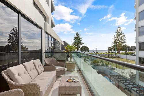 a balcony with a couch and chairs on a building at Marvelous Downtown Apartment Moments from Main Beach with Heated Pool, Gym and Parking in Mount Maunganui