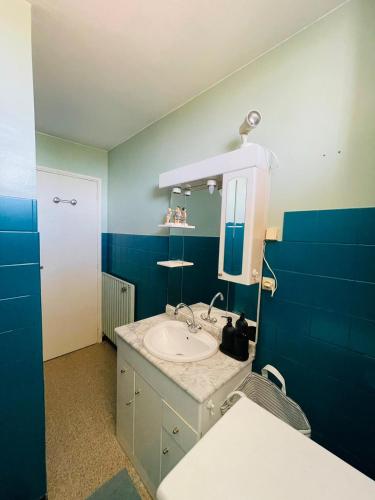 une salle de bain bleue avec un lavabo et un miroir dans l'établissement Blue Paradise, à La Ciotat