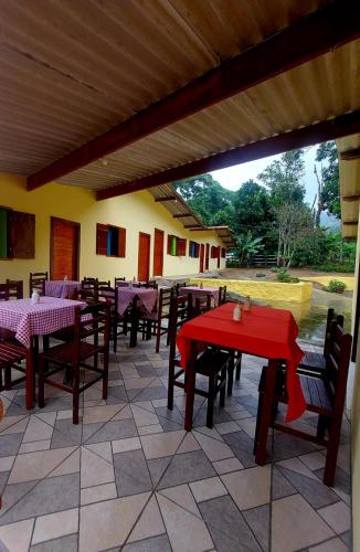 ein Restaurant mit Tischen und Stühlen und einem roten Tisch in der Unterkunft Pousada Sítio Monte Sinai in São José do Barreiro