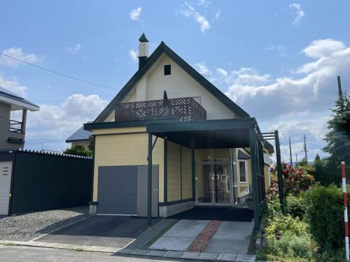 a small yellow and white house with a garage at Miyuki Townhouse in Furano