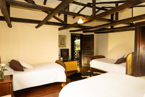 two beds in a room with wooden ceilings at Hacienda San Isidro Trails & Experiences in Cotacachi