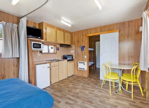 a kitchen with a table and yellow chairs in a room at South Goulburn Caravan Park in Goulburn