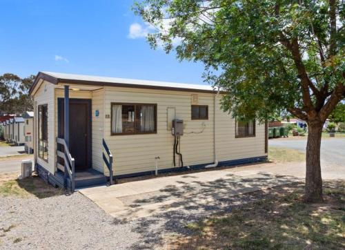 a small white house with a tree in front of it at South Goulburn Caravan Park in Goulburn