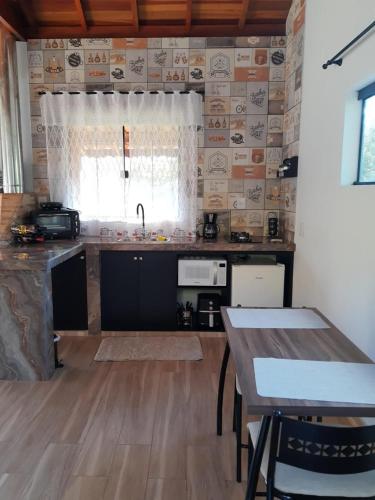 a kitchen with a sink and a table in a room at Chalés Recanto na Serra in Gonçalves