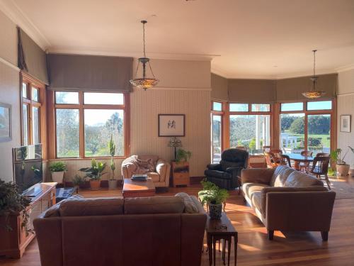 a living room with couches and chairs and windows at The Loft at Henton Lodge in Mauku