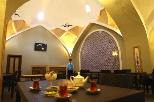 a man standing in a restaurant with tables and chairs at Vego Hotel in Ganja