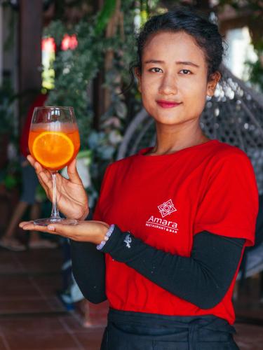 a woman holding a glass of orange juice at Amara Beach Resort Koh Phangan in Haad Yao
