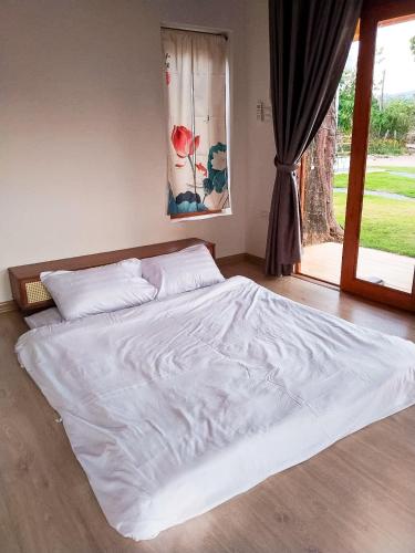 a large white bed in a room with a window at Sithaya Garden House @14 in Ban Thung Luang (1)