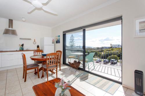 a kitchen and dining room with a table and a balcony at Cottesloe Seaside Bliss in Perth