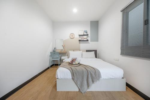 a white bedroom with a bed and a table at Spacious 4BRTownhouse BTS Onnut 10 Sleeps with Parking in Amphoe Phra Khanong