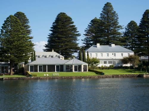 a large white house with a lake in front of it at Douglas Riverside in Port Fairy