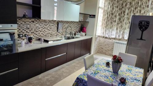 una cucina con tavolo, lavandino e frigorifero di Casa Stella a Palermo