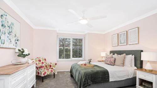 een slaapkamer met een bed, een stoel en een raam bij Coachwood Cottage in Robertson