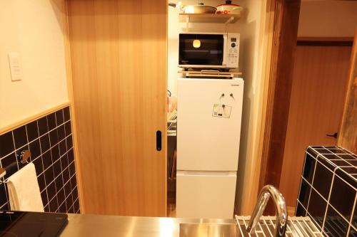 a kitchen with a white refrigerator and a microwave at まほろの宿 - 明日香村のリノベーション古民家一棟貸し in Asuka